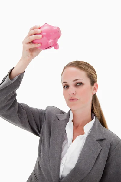 Сотрудница банка держит копилку над головой — стоковое фото