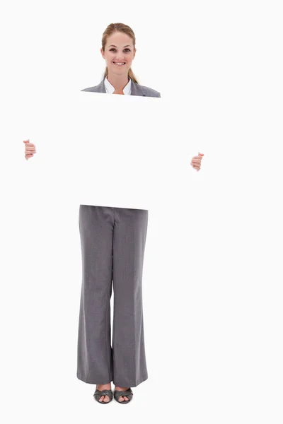 Smiling bank employee with blank sign in her hands — Stock Photo, Image