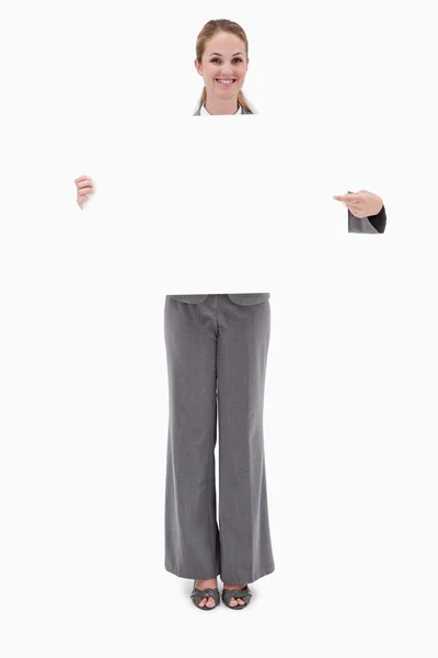 Smiling bank employee holding and pointing at blank sign — Stock Photo, Image