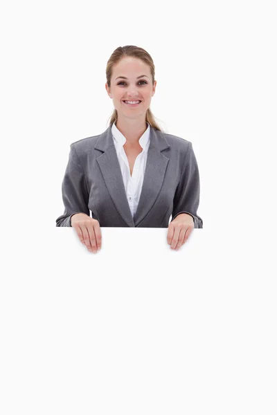 Smiling bank employee holding blank sign in her hands — Stock Photo, Image