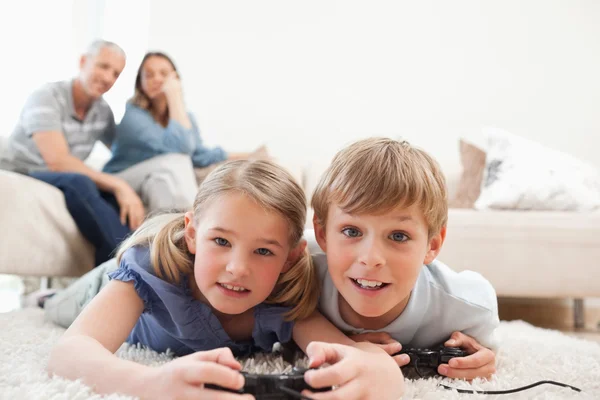 Bambini giocosi che giocano ai videogiochi con i loro genitori sul b — Foto Stock