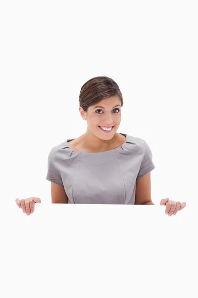 Smiling woman looking over blank wall — Stock Photo, Image