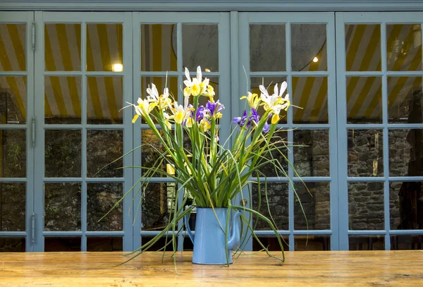 Schöne Frühlingsblumen in einer blau emaillierten Teekanne auf dem Holz — Stockfoto