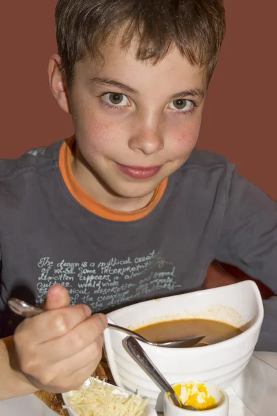 Süßer Teenager-Junge isst Suppe zum Abendessen — Stockfoto