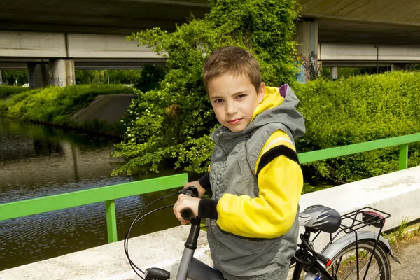 Joven linda escuela chico con bicicleta en el puente — Foto de Stock