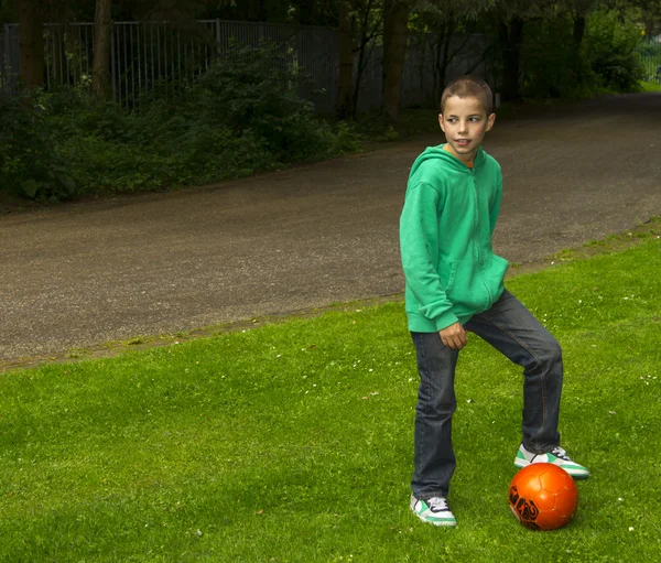 Jovem menino bonito com bola de futebol laranja — Fotografia de Stock