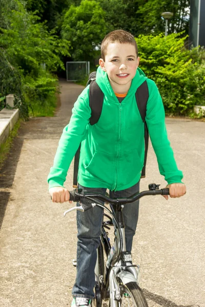 Menino da escola jovem com mochila em uma bicicleta — Fotografia de Stock