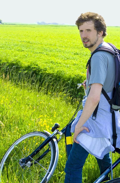 Man cyclist relaxing against the background of green fields in s — Stock Photo, Image