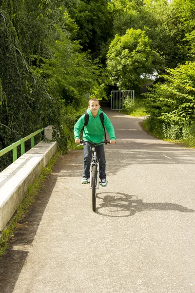 Молодой школьник с рюкзаком на велосипеде — стоковое фото