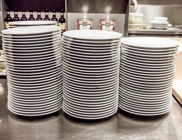 Stacks of white plates against a restaurant background — Stock Photo, Image