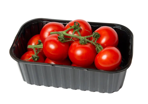 Tomates vermelhos em uma caixa de plástico escuro, é isolado no branco — Fotografia de Stock