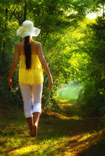 Ung kvinna gå på vägen i skogen — Stockfoto