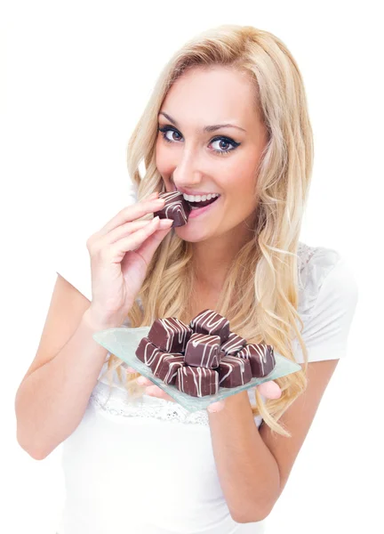 Young woman eating pralines, studio-shot — Stock Photo, Image