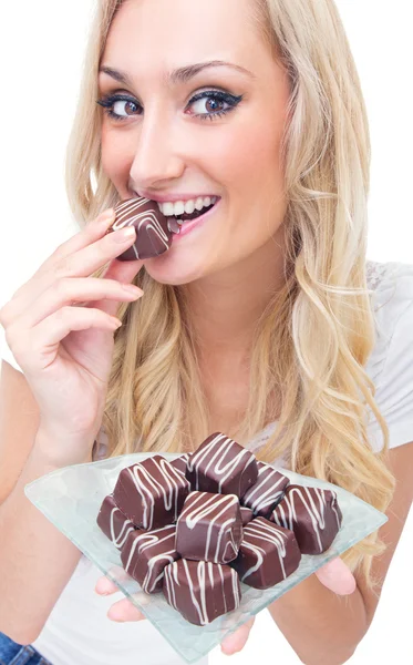 Mladá žena jíst pralinky, studio-shot — Stock fotografie