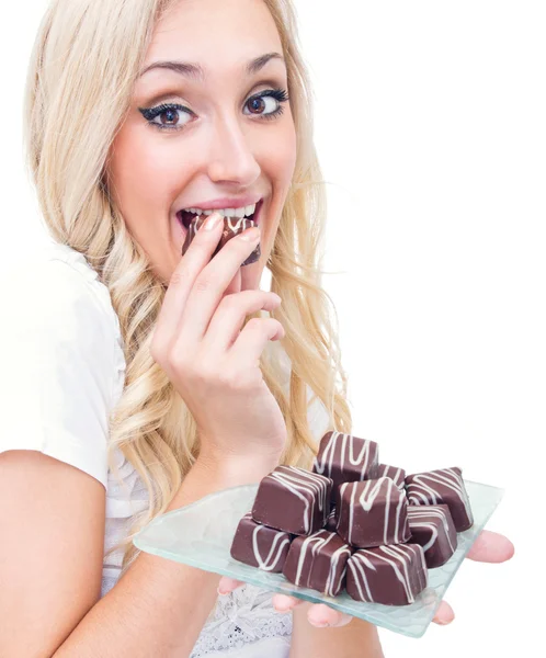 Mladá žena jíst pralinky, studio-shot — Stock fotografie