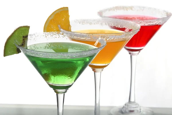 stock image A close up view of martini glass with different colored cocktails and a piece of orange