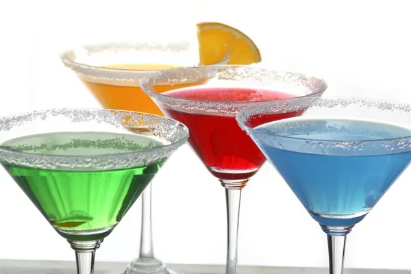 Uma vista de perto de vidro martini com diferentes coquetéis coloridos e um pedaço de laranja — Fotografia de Stock