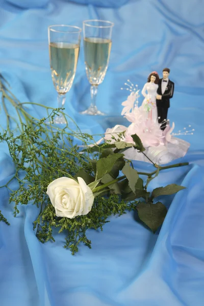 Μια φωτογραφία της κούκλες γαμήλια τούρτα, αυξήθηκε και γυαλιά πάνω από το μπλε — Φωτογραφία Αρχείου