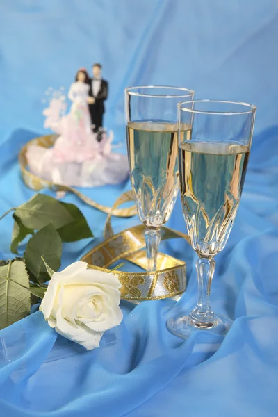 A photo of wedding cake dolls, rose and glasses over blue — Stock Photo, Image