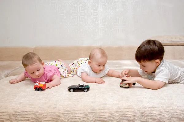 Hermanas gemelas bebé niñas y su hermano jugando —  Fotos de Stock