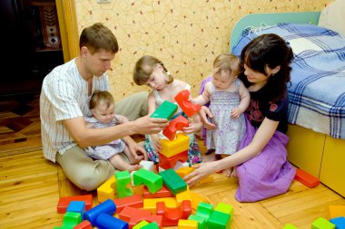 Big family building a house from toy cubes clipart