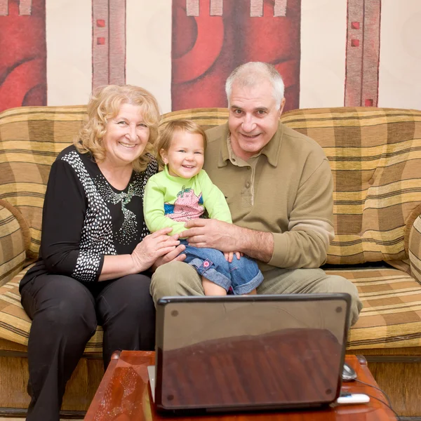 Bestemor, bestefar og barnebarn ser på filmen – stockfoto