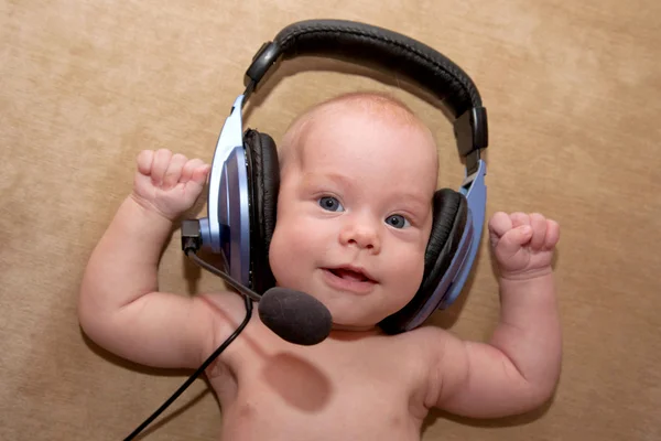 Bonito bebé recién nacido con ojos azules sonriendo con un auricular . — Foto de Stock