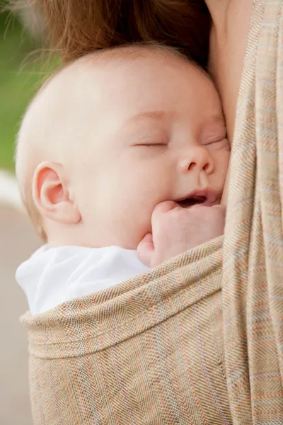 Nyfödda barn sover i en sele — Stockfoto