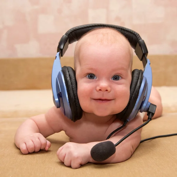 Bonito bebé recién nacido con ojos azules sonriendo con un auricular . —  Fotos de Stock
