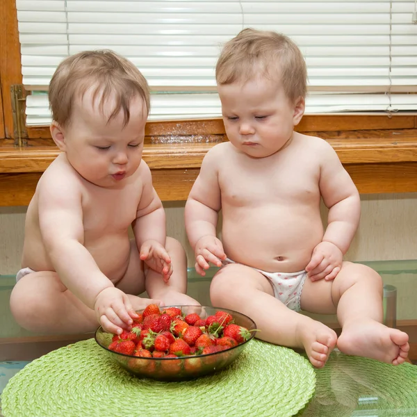 Twins eating strawberries — Stock Photo, Image
