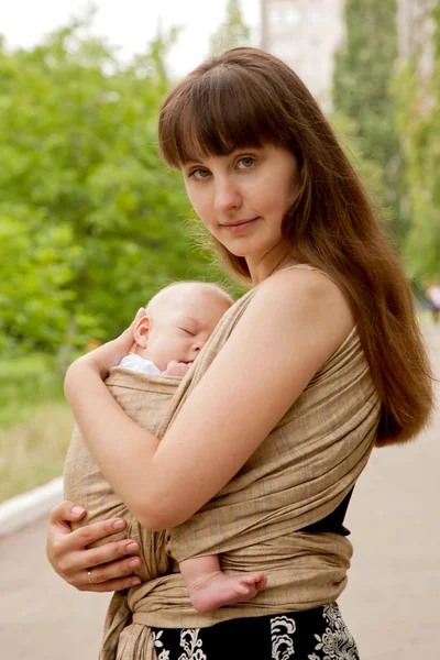 Novorozené dítě v šátku, v objetí matky. — Stock fotografie