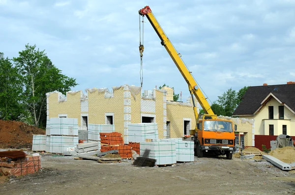 Bau des neuen Hauses mit einem Kran. lizenzfreie Stockfotos