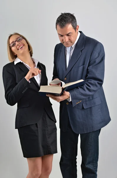 Schöne Geschäftsfrau mit einem männlichen Kollegen, der ein Buch liest — Stockfoto