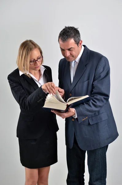 Jovem mulher de negócios com colega masculino lendo um livro — Fotografia de Stock