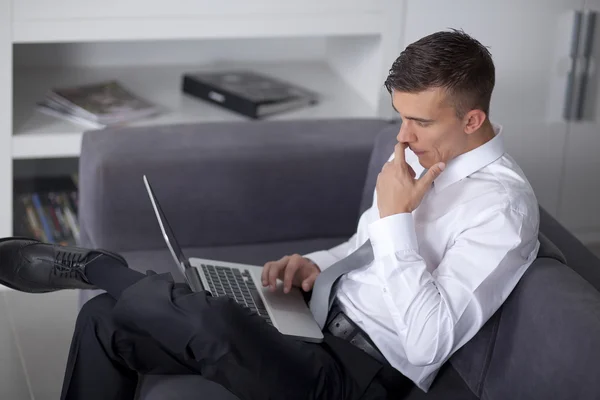 Glad affärsman arbetar med en bärbar dator och sitter på soffan — Stockfoto