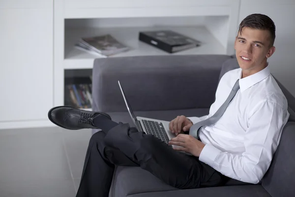 Happy businessman working with a notebook and sitting on couch — Stock Photo, Image