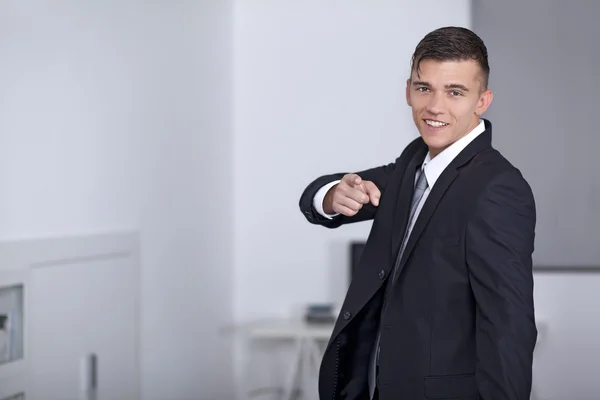 Lachende zakenman in pak poseren en hand gebaren punt — Stockfoto