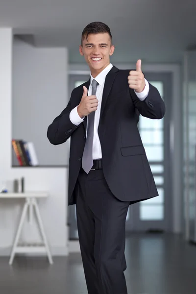 Empresário em poses de terno e mão gesto polegar para cima — Fotografia de Stock