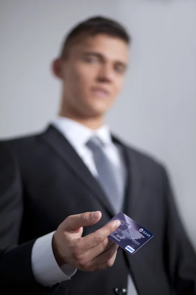 Joven sonriente empresario exitoso sosteniendo una tarjeta de crédito — Foto de Stock