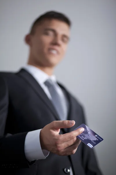 Молодий усміхнений успішний бізнесмен тримає кредитну картку — стокове фото
