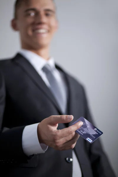 Young smiling successful businessman holding an credit card — Stock Photo, Image