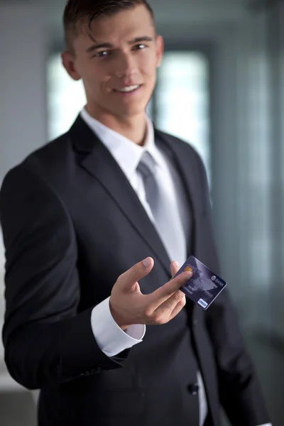 Joven sonriente empresario exitoso sosteniendo una tarjeta de crédito — Foto de Stock