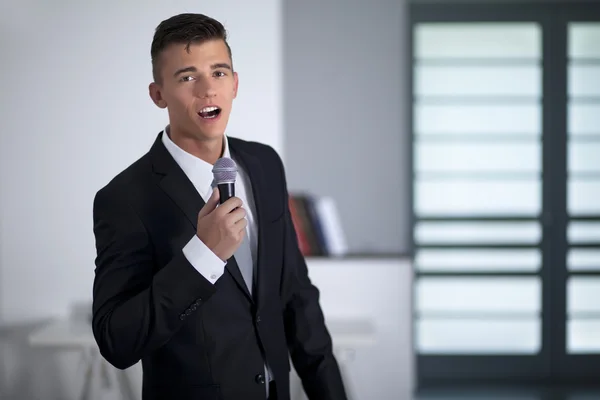 Ung affärsman sjunga med en mikrofon i office — Stockfoto