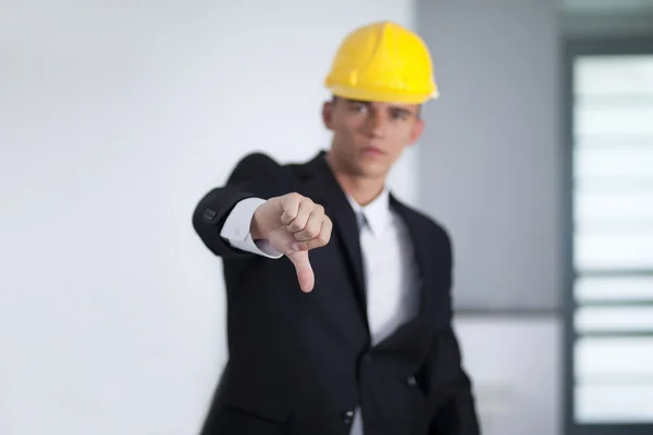 Young businessman wearing a safety hat and hand gesturing thumbs — Stock Photo, Image