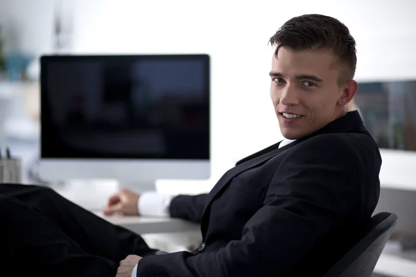 Joven hombre de negocios trabajando con un ordenador y sentado en el sofá —  Fotos de Stock