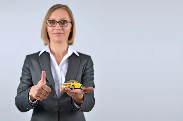Femme d'affaires tenant et montrant une voiture jouet sur sa main — Photo