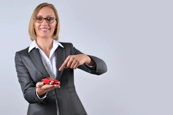 Imprenditrice che tiene in mano e mostra un'auto giocattolo — Foto Stock