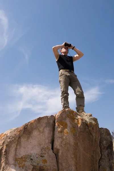 Man looks into binoculars — Stock Photo, Image
