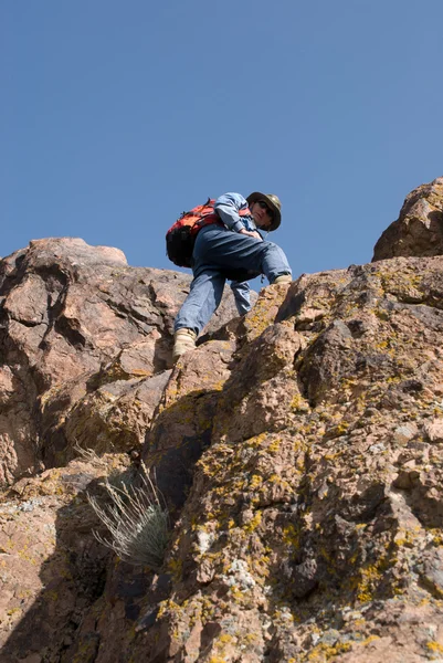 The tourist rises on a rock — Stock Photo, Image