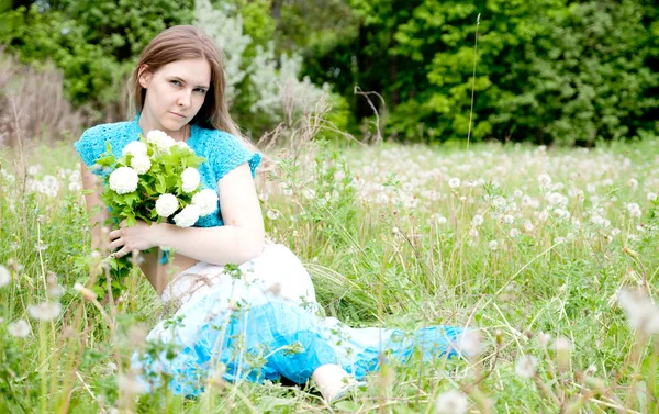 Fashion Ukrainian girl is sitting on the field with flowers — Stock Photo, Image